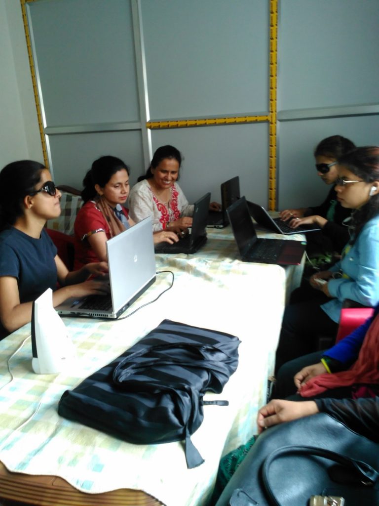 A group of women sitting around the table and using the laptop.