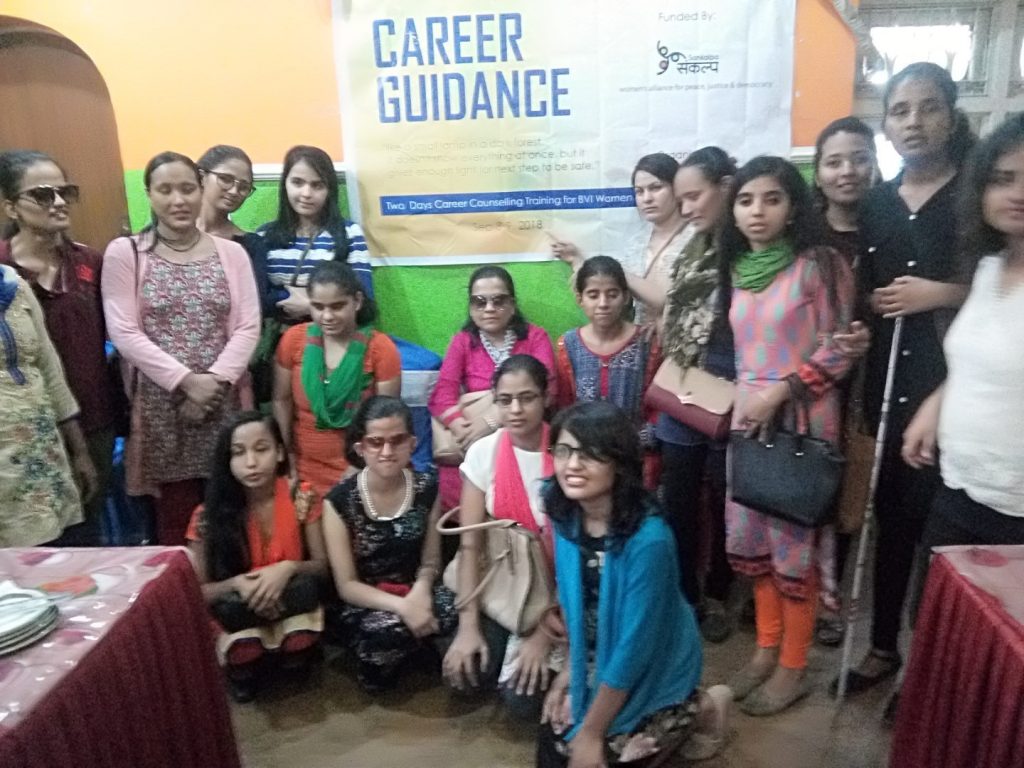 A group of ladies is standing and sitting in front of the program banner.