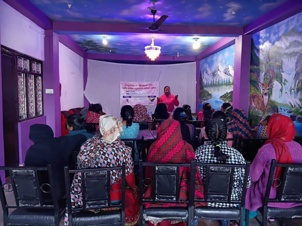 Narayani Saha is leading the session. A banner is visible at the front, and almost all participants are visible in the photo.